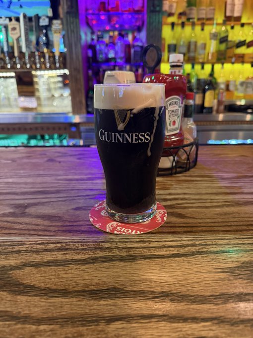 A pint of Guinness sits on a coaster at a bar next to a bottle of Heinz Tomato Ketchup, with the text "Never kill yourself" suggesting encouragement not to give up on life, perhaps finding solace in enjoying a drink at the pub.