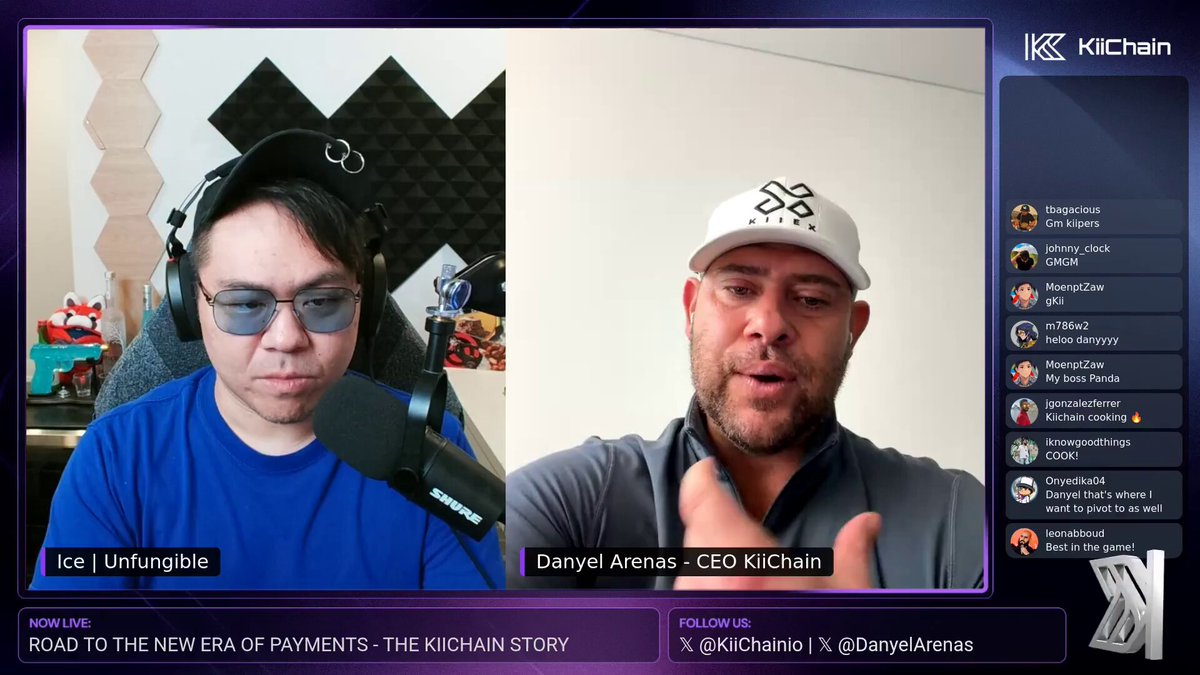 The image shows a screen displaying two men wearing baseball caps, with one man speaking into a microphone while the other listens attentively. The background of the image features a purple wall adorned with geometric shapes. In the bottom right corner of the image, there is text that reads "@KiiChainio @DanyelArenas breaking down the road to the new era of payments and onchain FX This is why @KiiChainio is cooking".