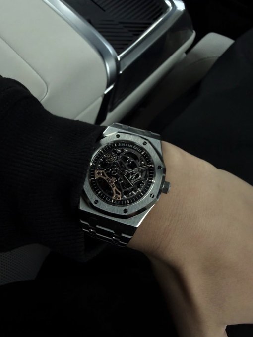 A person wears a luxury silver Audemars Piguet Royal Oak skeleton watch on their wrist inside a vehicle. The image conveys wealth and success, fitting the post's "GM" giveaway offering $80 to a new follower—a subtle flex intended to attract engagement.