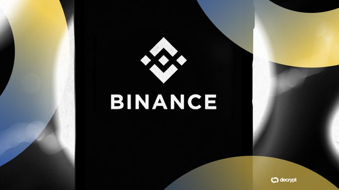 The image features a logo with the word "Binance" written in white letters, surrounded by circles of different colors including yellow, blue, and black. The background of the image has a gradient effect that transitions from yellow at the top to blue at the bottom. There is also text on the image that reads: "Just In: Binance opens access to 7,000 US stocks and previews tokenized 
bStocks" for non-US users.".