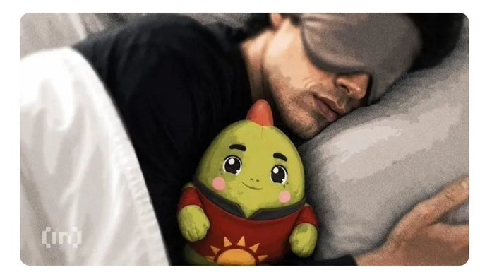 A man wearing a sleep mask is sleeping in bed next to a plush avocado character wearing a red shirt with a sun design, with an '{in}' watermark in the corner.
