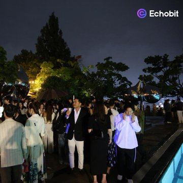 A crowd of people gathers outdoors at night beneath trees, with the "Echobit" logo in the upper right corner.