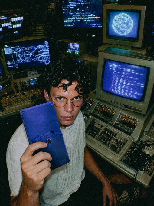 urn of a computer monitor displays blue and white text, with the man holding a blue tablet above it.