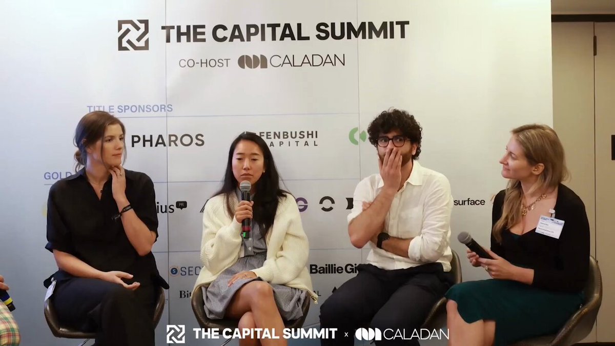 The image shows four people sitting around a table at an event, likely participating in a panel discussion or interview. They are all wearing business attire, which suggests that they might be professionals from different fields. One of them has a microphone, indicating that they are conducting an interview or panel discussion. The backdrop features the words "The Capital Summit" and logos for companies like Centrifuge and Onchain Credibility. This event seems to be focused on discussing business strategies and sharing insights among industry experts.