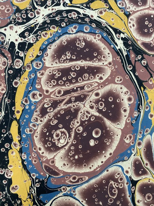 An abstract marbled art piece featuring swirling patterns of brown, blue, yellow, and black with bubbly textures.
