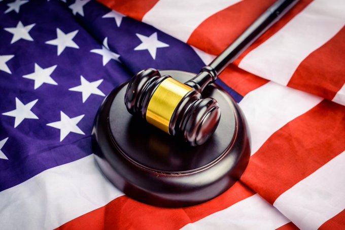 A wooden judge's gavel rests on a draped American flag, symbolizing the ongoing legislative debate in the U.S. Senate over the proposed CLARITY Act. The image evokes the legal and political tensions surrounding the bill as Democrats have yet to sign on before the August recess.