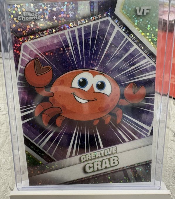 The image features a plastic card with a cartoon crab design, which is the centerpiece of the frame. The crab has a big smile on its face and appears to be smiling at something or someone. Above and below the crab photo are text that says "Creative Crab" in black, indicating it's an illustration for a product named "Creative Crab Blast Off". Below this description is another line of text stating that the crab "has been pulled!". The post also mentions selling the card for $1300 but does not provide any further information about the price.