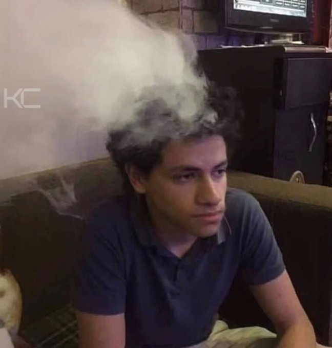 A young man sits on a couch while exhaling a large cloud of smoke/vapor, with a 'KC' watermark visible in the corner of the image.