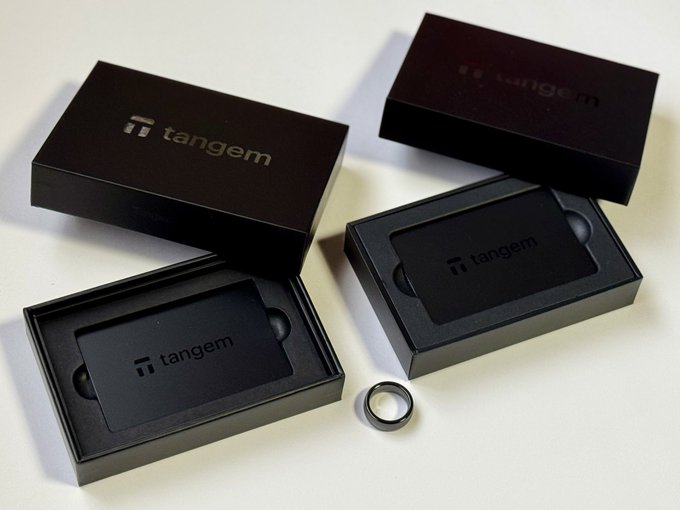 Two black Tangem wallet boxes are displayed open, each containing a sleek black Tangem card with the brand's logo, accompanied by a metal ring accessory. The image illustrates the seedless hardware wallet featured in the post, showcasing its durable, minimalist design that the user praises for its 25-year warranty and ease of use.