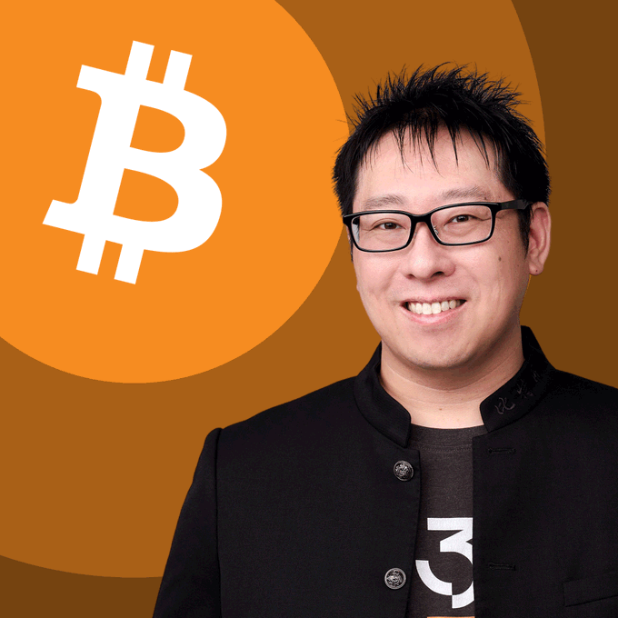 A smiling man wearing glasses and a black jacket stands beside the Bitcoin logo (₿) on an orange circular background, with what appears to be "RSK" visible on his shirt. The image relates to Samson Mow's quote about Bitcoin volatility being essential vitality, visually pairing him with the cryptocurrency's iconic symbol.