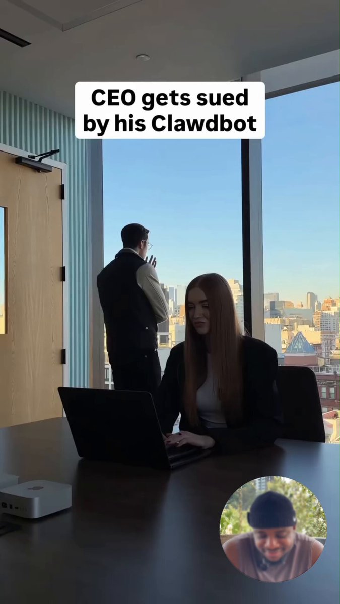 The image shows a man sitting at a desk with his laptop open while another person stands behind him. The scene takes place in an office setting, as indicated by the presence of chairs and desks. A window can be seen in the background, providing natural light to the room. The caption reads "CEO gets sued by his Clawbot", which is likely a reference to a popular video game or movie involving a robot character suing its CEO for damages.