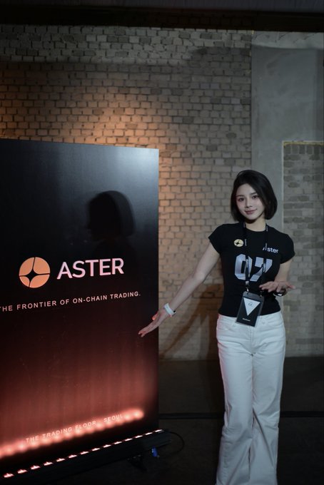 A woman stands next to an ASTER promotional banner reading 'THE FRONTIER OF ON-CHAIN TRADING' at what appears to be a crypto event.