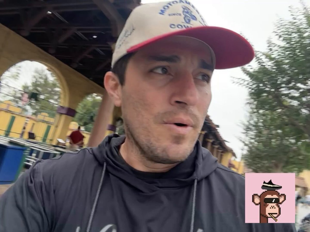 The image features a man wearing a baseball cap with a logo of a monkey on his head. He appears to be looking at something or someone off-camera, possibly engaged in conversation or observing an interesting sight. The caption below the photo reads "Don't be a Westin, Be a Cosmic $HBAR". This phrase is likely a reference to the popular video game series "Westworld" and its theme of exploring alternate dimensions and encountering various characters from different planets.