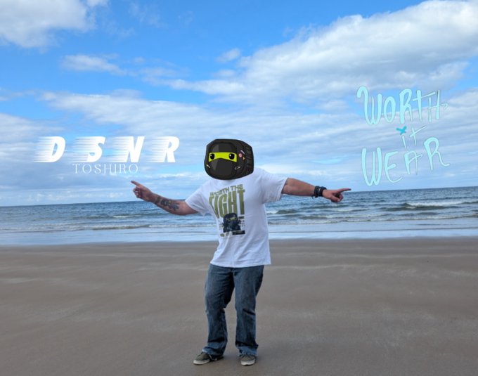 A person stands on a beach wearing a VR headset with arms outstretched, with text reading "DSNR TOSHIRO" and "WORTH IT WEAR".