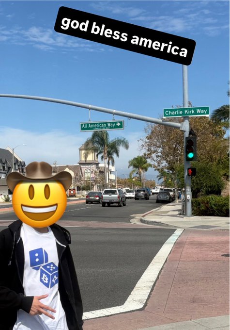 A person wearing a cowboy hat and a Domino's t-shirt (face covered by a smiley emoji) stands at an intersection with street signs reading "All American Way" and "Charlie Kirk Way," beneath an overlay text reading "god bless america." The image references the blockchain post by visually embodying patriotic Americana iconography — combining American brands, politicians' names, and a wholesome emoji — to symbolize values being recorded "on the blockchain."
