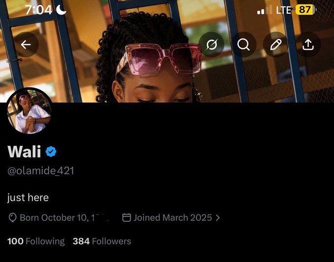 A Twitter/X profile page for "Wali" (@olamide421) with a blue verification checkmark, displaying a bio that reads "just here," showing 100 Following and 384 Followers, alongside a header photo of a woman wearing pink sunglasses. The profile appears to belong to a new user who recently joined in March 2025 and is celebrating a subscription milestone in the accompanying post.