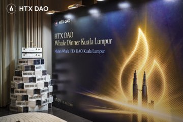 An event photo from HTX DAO showing a 'Whistle Dinner Kuala Lumpur' backdrop featuring the Petronas Twin Towers, with stacked boxes on the left side.