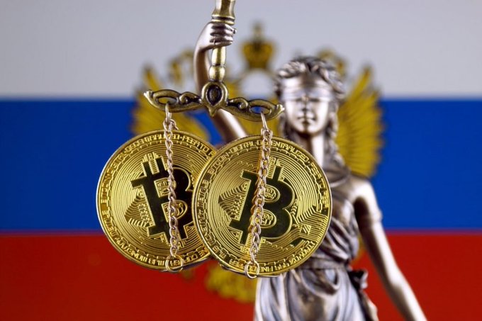 Two golden Bitcoin coins hang from chains held by Lady Justice, with the Russian flag and a golden double-headed eagle emblem in the background. The image visually reinforces the post's message about Russia moving to finalize cryptocurrency regulation, symbolizing the balance of justice and legislative authority over the growing crypto industry that global powers are advancing.