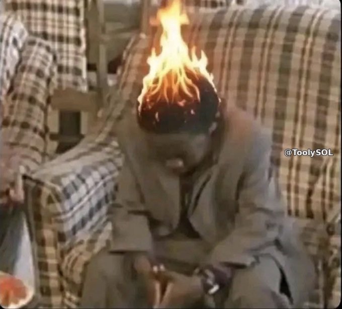 A blurry, low-resolution clip of a person sitting on a plaid couch with their head engulfed in flames, watermarked "@ToolySOL".