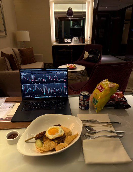 A laptop displays stock market charts in a hotel room, accompanied by a meal and a can of Pepsi, awaiting a Federal Reserve decision that will influence trading strategies. The scene depicts a trader's pre-decision preparation, as mentioned in the accompanying post.