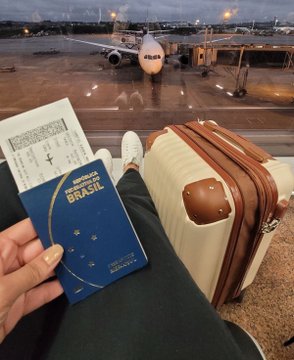 A traveler holds a Brazilian passport and boarding pass at the airport with a suitcase nearby, symbolizing international travel and the global nature of credit and financial systems discussed in the post about cross-border lending and identity.