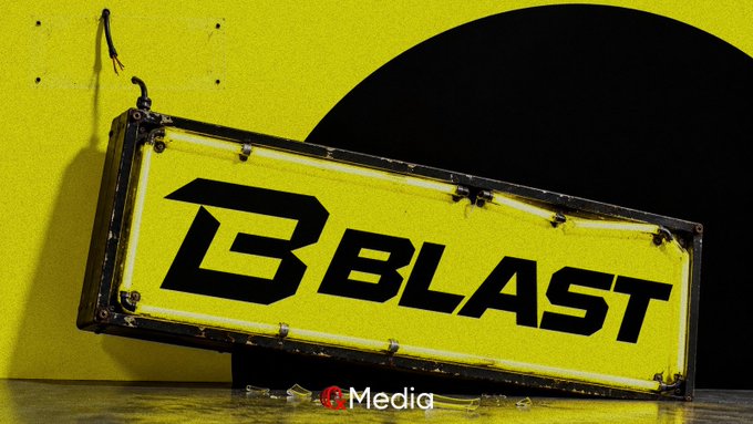 A bright yellow illuminated billboard displays the 'B BLAST' logo in bold black text, mounted against a yellow wall with a dark archway in the background, and a small 'Media' watermark is visible at the bottom.