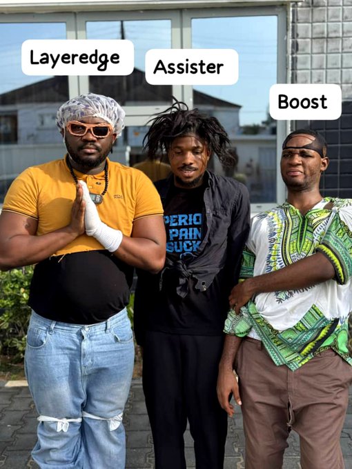 Three men standing together outdoors labeled "Layeredge" (in yellow shirt with shower cap and sunglasses), "Assister" (in dark shirt with dreadlocks), and "Boost" (in green patterned dashiki with backward cap), parodying gaming terminology.