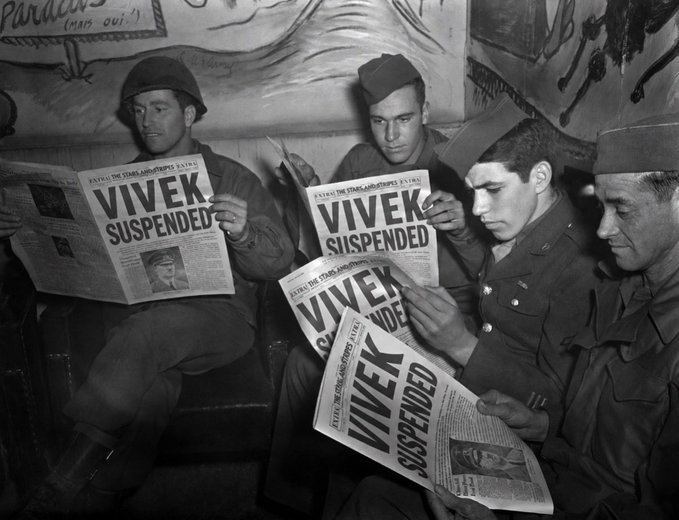 A black and white historical photograph showing four soldiers reading newspapers with the headline 'VIVEK SUSPENDED' about the cancellation of the 1948 Olympics in London.