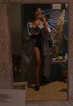 A woman takes a mirror selfie wearing a sheer silver robe over a black outfit, paired with platform heels. The image accompanies a post celebrating #TEZOSTUESDAY and promoting her "Self Study" 1/1 sketches collection on objkt.com.