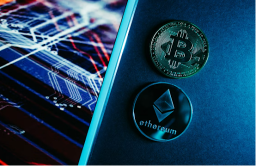 A Bitcoin and an Ethereum coin rest on a dark surface beside a screen displaying stock chart lines, visually anchoring the post's message that institutional narratives around crypto like BTC and ETH no longer translate into capital inflows without real money following.