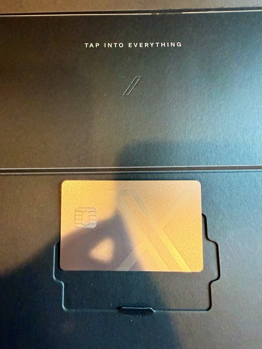A close-up photo of an HP laptop with 'TAP INTO EVERYTHING' printed on the lid, featuring a metallic card with an X logo and chip sitting in a tray slot.