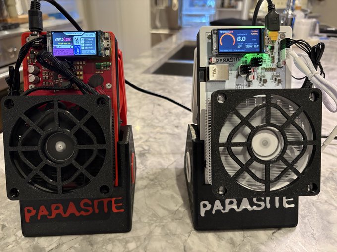 Two cryptocurrency mining devices (ASIC miners) branded 'PARASITE' sit on a marble countertop, one in red and one in clear/transparent casing, each with cooling fans on the front.