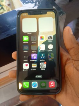 A hand holds a new iPhone XR displaying its home screen with a "Search" bar visible at the bottom, aligning with the post about getting the phone as a gift for his sister who will be joining Web3 next month.