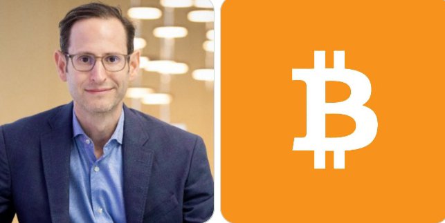 A bespectacled man in a blue blazer stands beside a large orange panel displaying the white Bitcoin (₿) logo. This image accompanies a post featuring VanEck's Matthew Sigel, who predicts Bitcoin could reach $100K next year and potentially $500K by 2029.