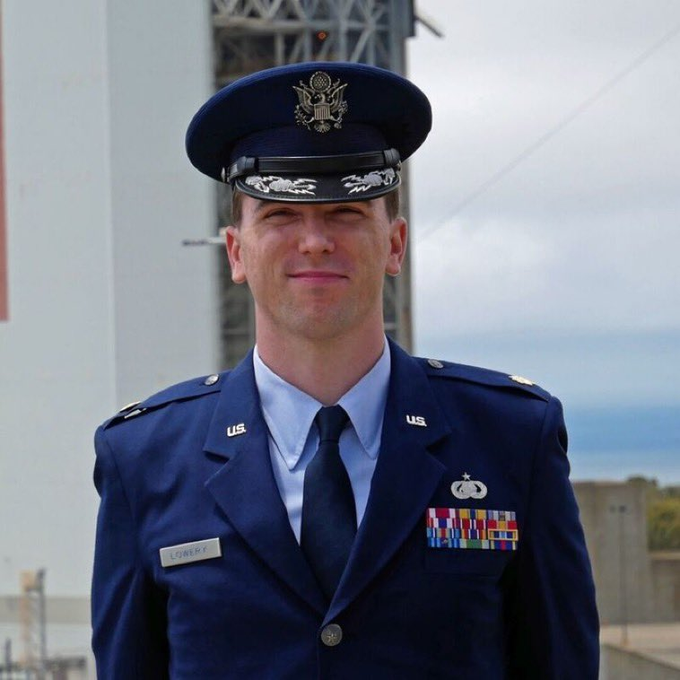 A US Air Force officer named Jason Lowry stands by a government building wearing a uniform full of medals and badges. The caption references his views on Bitcoin's impact on traditional financial systems, aligning with the individual's service in an institution that maintains economic stability, while his critique suggests an alternative perspective on the value of digital currencies like Bitcoin.