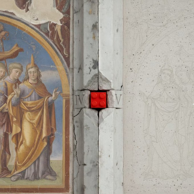 A section of a classical religious fresco depicting a robed figure with a halo, partially faded, next to a cracked marble wall adorned with a small red Lego brick between the Roman numerals 'IV' and 'V'.