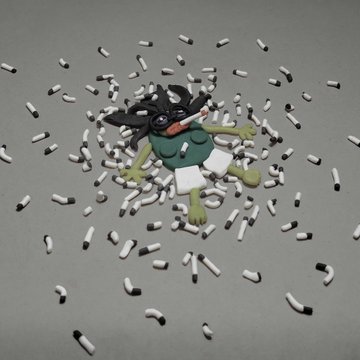 A dark-haired cartoon character lying on a gray floor surrounded by scattered domino pieces.