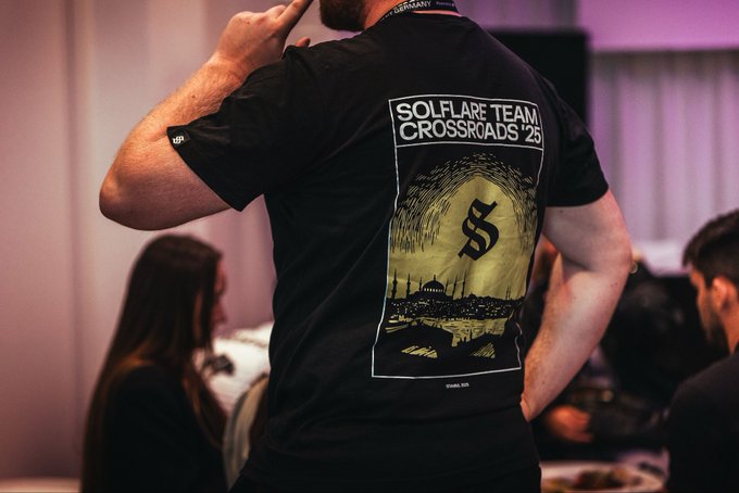A person from behind wearing a black t-shirt that reads 'SOLFLARE TEAM CROSSROADS '25' with a graphic of the Golden Gate Bridge and the Solflare 'S' logo.