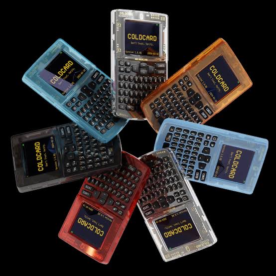 Seven colorful, transparent handheld electronic devices, labeled 'COLD CARD', arranged in a circular pattern against a black background.