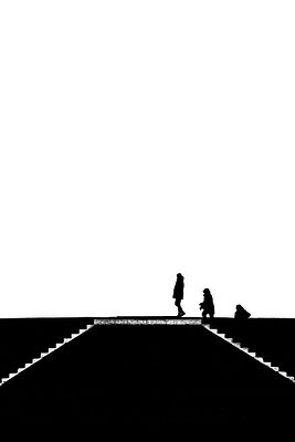 A high-contrast black and white silhouette image shows two figures walking a dog along a road with crosswalk markings.