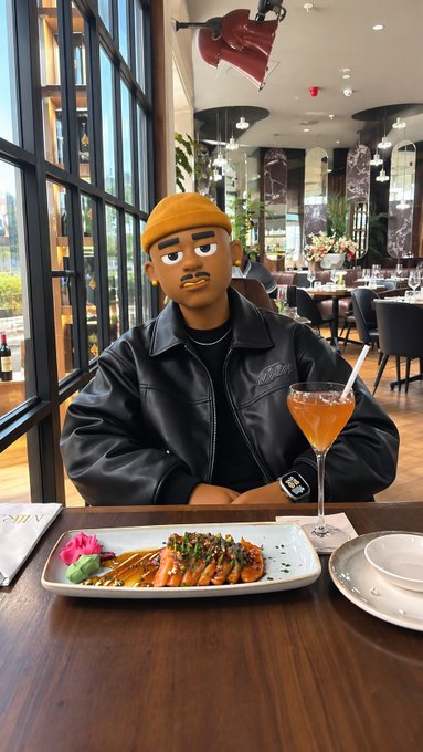 An emoji-masked person wearing a black leather jacket and yellow beanie sits at a restaurant table with a plated dish, a cocktail, and an Apple Watch visible on their wrist.