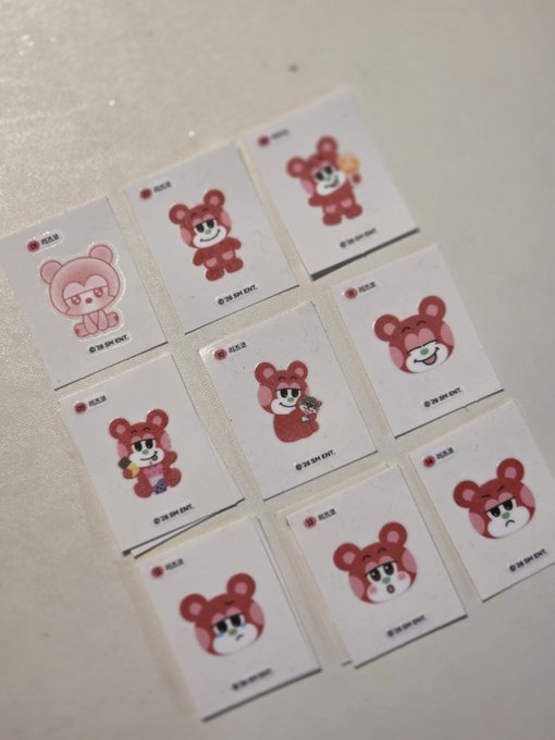 A collection of nine small square stickers featuring cartoon red bear characters in various poses and expressions, with '© SK ENE ENT.' text visible.