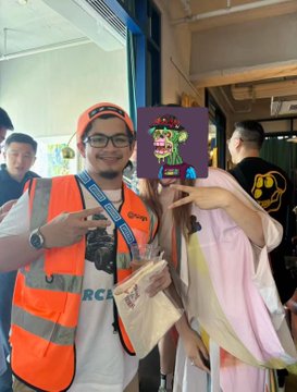 A man wearing an orange "PRESS" vest and Bored Ape-themed cap poses alongside a woman holding a purple sign featuring a Bored Ape NFT illustration, capturing a moment from the "Ape Into Asia" tour stop in Shanghai.