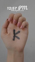 A hand with the letter 'K' written on it, with digital text overlay reading '12:57 pm Wednesday 02 June'.