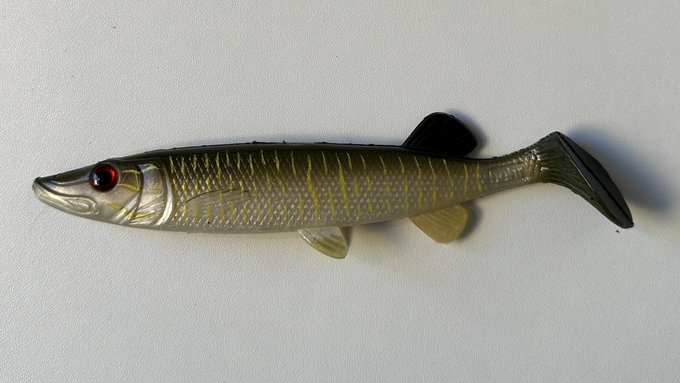 A close-up of a realistic fish-shaped object, resembling a small lure, lies on a plain white surface. The image serves as a visual metaphor for the post’s “lookalike address” address-poisoning scam, where one wrong character can redirect USDT funds.