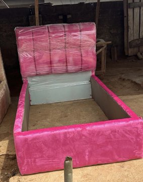 A bright pink upholstered bed frame, still wrapped in plastic, sits empty in a workshop, representing the "big girl purchase" the poster credits to their success in Web3. The luxurious, feminine design reflects a personal milestone made possible by crypto earnings.