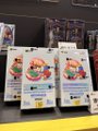 A small low-resolution image showing what appears to be Pokémon trading cards displayed on a shelf or rack.