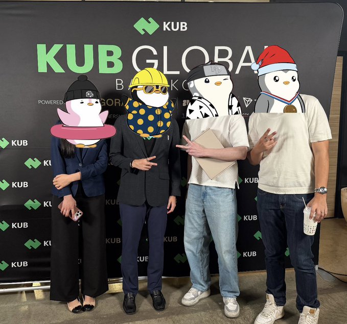 Four people pose in front of a 'KUB GLOBAL' banner, their faces covered by cartoon animal/penguin sticker emojis.