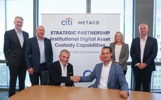 Executives from Citi and Metaco (a Ripple company) shake hands at a contract signing ceremony for a strategic partnership to develop institutional digital asset custody capabilities. The banner behind them reads "CITI METACO – Strategic Partnership – Institutional Digital Asset Custody Capabilities."