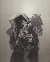 Black and white vintage photograph of a woman in an ornate, flowing dress posing in a dramatic, blurry style.